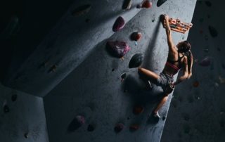 Young woman in shorts and sports bra exercising on a bouldering wall indoors.